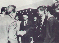 JFK meeting Rat Pack members & others outside the Sands Hotel, Las Vegas, Feb 1960. From left, clockwise: film director Lewis Milestone (back turned) Dean Martin left of Milestone, shaking hands with JFK, Buddy Lester, Joey Bishop center, Sammy Davis, Jr., partially hidden by Kennedy's arm, Kennedy, and Frank Sinatra.