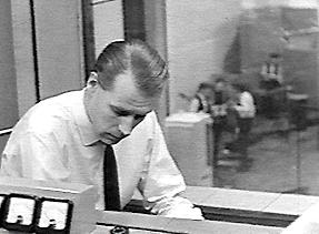 1963: George Martin in a sound booth at Abbey Road studios with the Beatles in the background.