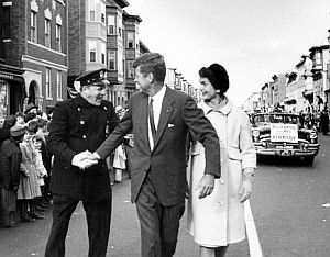 1958: Senator Kennedy & Jackie greeting Boston police officer on Chelsea Street in East Boston during Columbus Day parade.