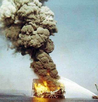 December 1970: Shell offshore oil rig in collapsed state, being sprayed with water as fire continues. Photo, Bob King, from Coast Guard cutter, ‘Dependable’.