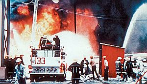 Fireman on firetruck No. 133 and other men fighting blaze at Gulf Oil refinery, photographed not long before this area went up in flames, destroying the firetruck and killing some of the firefighters.