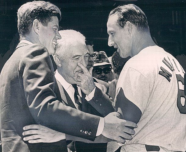 After he became president, JFK and St. Louis slugger Stan Musial, visit briefly before the July 1962 All-Star Game in Washington, where Kennedy threw out the ceremonial game ball. Baseball Commissioner Ford Frick is at center.  Musial in the All Star game would have a base hit that led to a run.  That year he would compile a .330 average. 