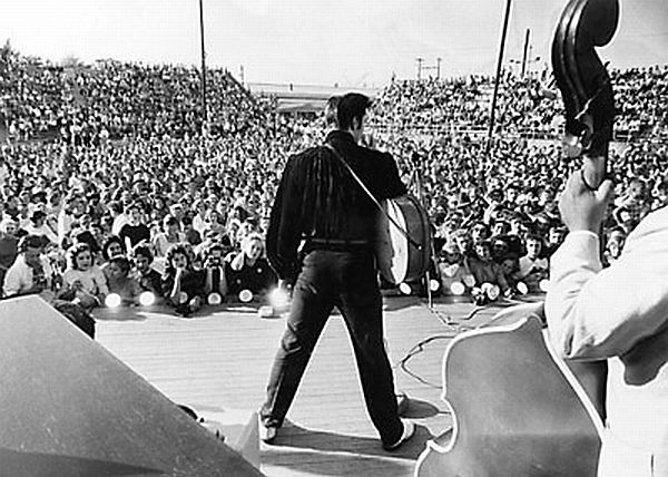 Elvis performing before capacity crowd at the Mississippi-Alabama Fairgrounds, Tupelo, MS, September 26, 1956. Click for framed, two-photo collage of Elvis - 1 performing, 1 portrait – plus listing of all No. 1 hits.