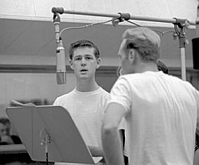 Young Brian Wilson at mic, early 1960s, with Mike Love, in recording studio.