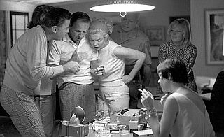 Marilyn Monroe, center, at Peter & Pat Lawford’s home in 1960-61, with Peter Lawford left and Frank Sinatra next to Monroe looking at a photograph. May Britt is standing at right.