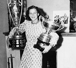 Babe Didrikson posing with two of her golf trophies in the 1950s.