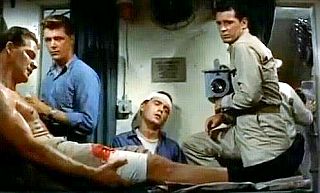 Frank Gifford, foreground, as Ensign Cy Mount, here injured, in 1959 James Garner film “Up Periscope.” Click for DVD.