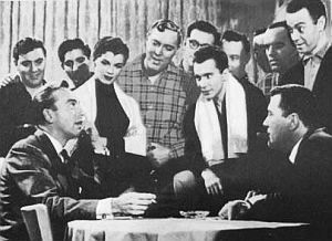 Scene from “Rock Around The Clock” with Bill Haley, center, plaid shirt & Alan Freed, upper right. Click for Haley story.