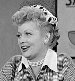 Lucy in a relaxed pose, as she begins to sample the health tonic “Vitameatavegamin” she is supposed to be selling in a famous 1956 “I Love Lucy” episode.