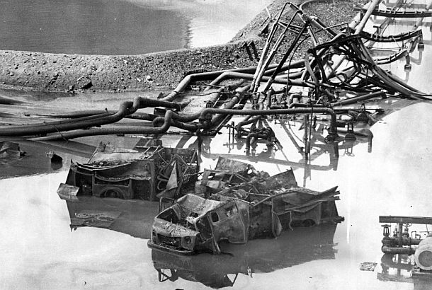 Philadelphia Evening Bulletin photo of burnt out and twisted remains of Gulf Oil refinery apparatus near storage tank earthen dike with fire truck and pumper skeletons in foreground, August 1975, Philadelphia, PA. 