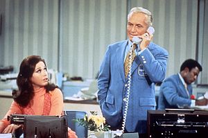 Mary Richards in the newsroom with Ted Baxter on the phone and weatherman Gordy Howard in the background.