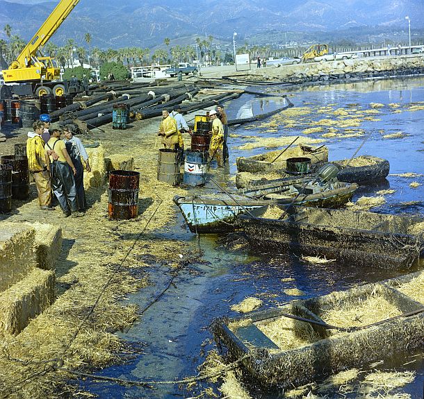 February 1969: Cleanup scene in Santa Barbara, California following oiled beaches there from Union Oil blowout.  Note black oil stain on jetty rocks at the top right portion of this photo. Bob Duncan, photo, via Flickr.com.