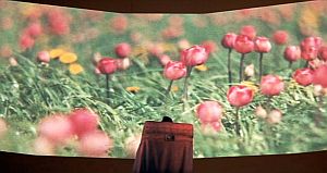 Gigantic film screen dwarfs Sol on his death bier (at center) as filmed images of the old “beautiful world” are shown accompanied by Tchaikovsky, Beethoven, and Grieg..